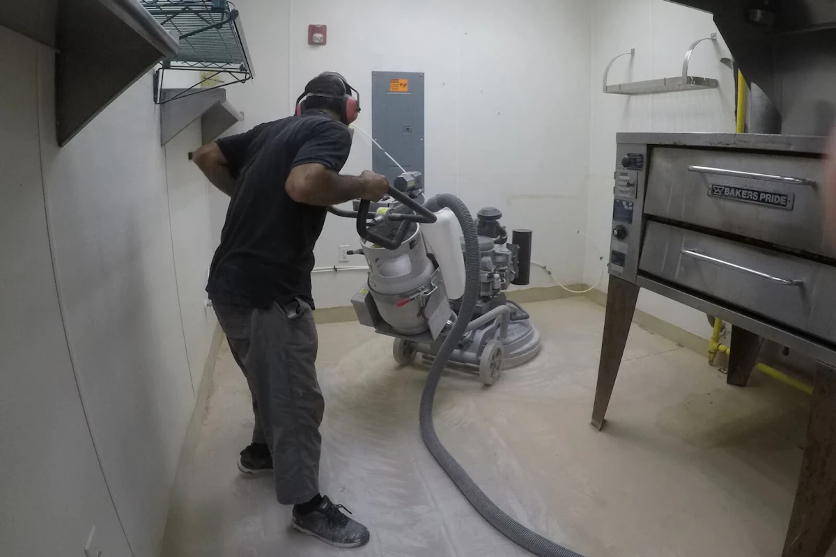 Man cleaning a floor that is being renovated.
