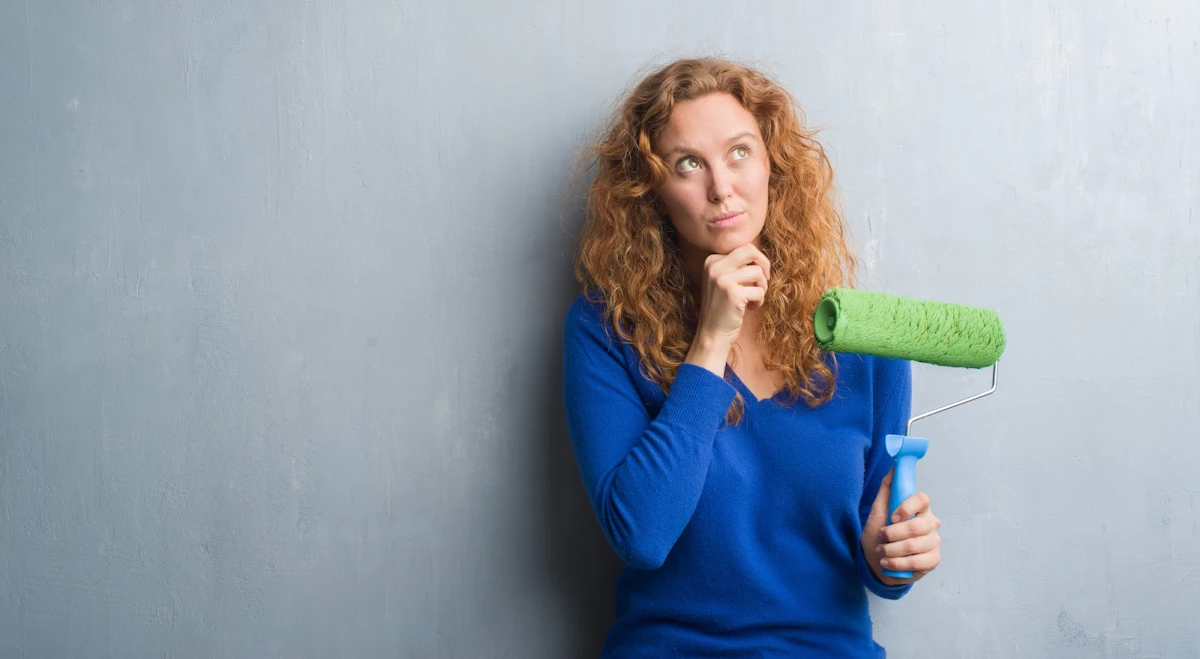 Woman holding up a green paint roller.