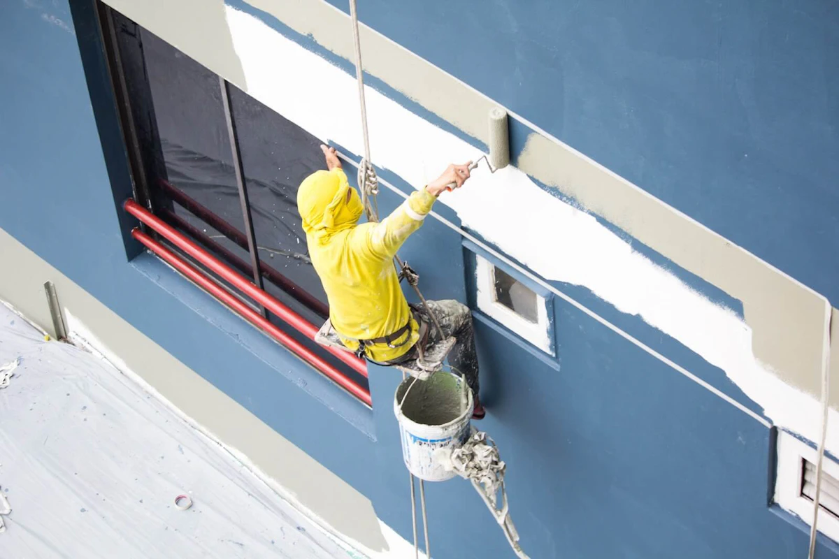 Contractor painting a commercial building blue